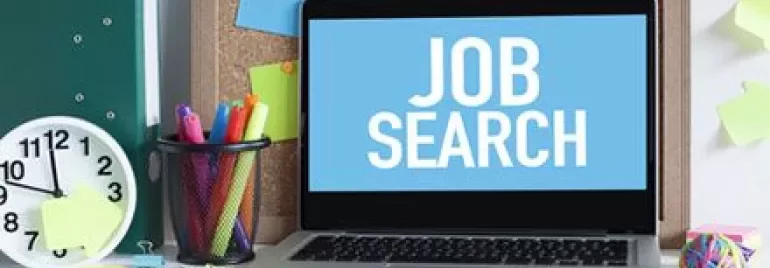 Laptop su scrivania con testo 'Job Search' sullo schermo.