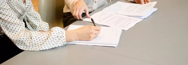 Due persone discutono documenti a un tavolo.