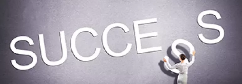 Persona in piedi che sistema la parola 'SUCCESSO'.
