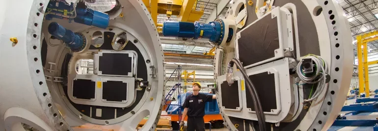 Lavoratore controlla grandi macchine industriali in un impianto.