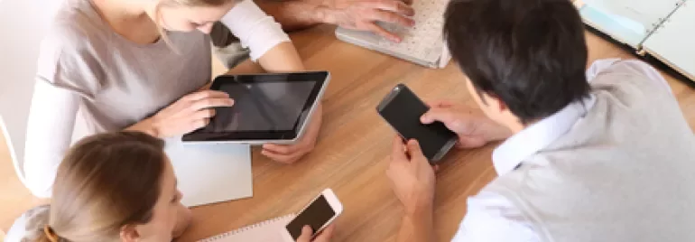 Persone che lavorano insieme con tablet e smartphone su un tavolo.