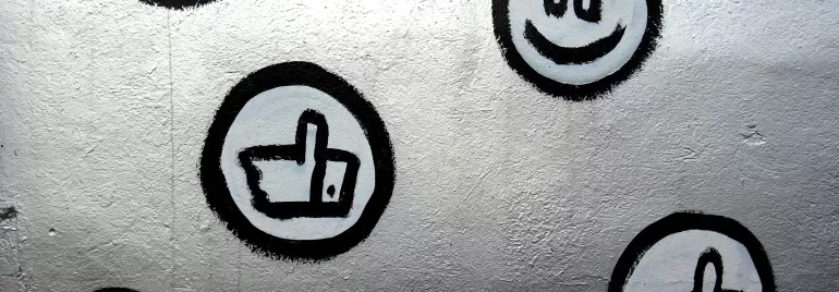 Murale con simboli di cuori e pollici su sfondo grigio.