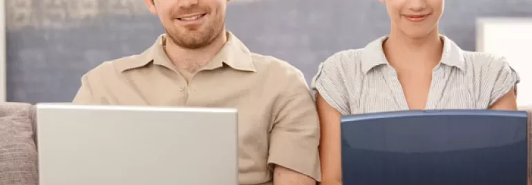 Due persone sedute con computer portatili.
