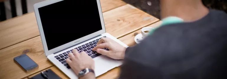 Persona al computer portatile in un caffè all'aperto.