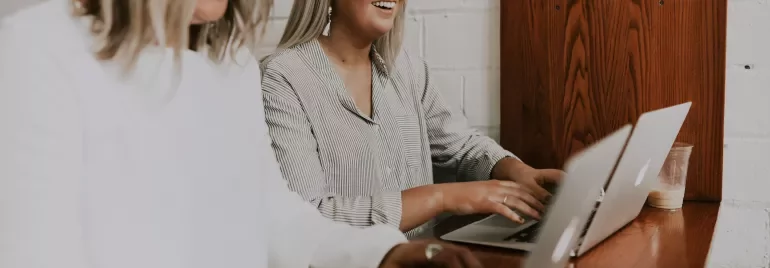 Persone lavorano insieme sui laptop al tavolo di legno.