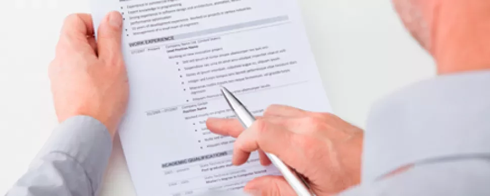Persona che esamina un curriculum con penna in mano