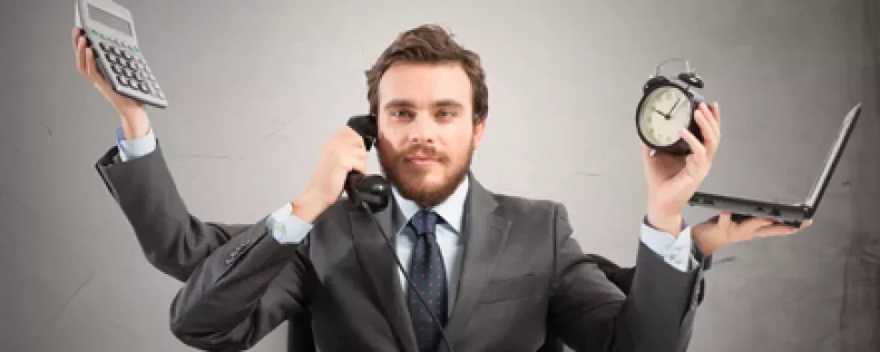 Persona multitasking con telefono, sveglia, calcolatrice e laptop.