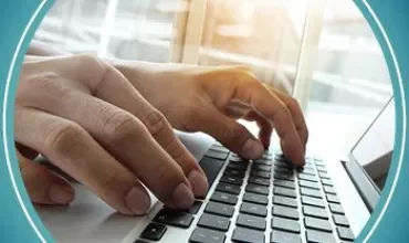 Mani che digitano su una tastiera di laptop con luce del sole.
