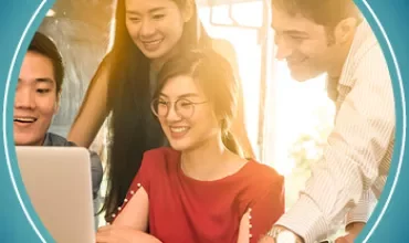 Gruppo di persone sorridenti intorno a un computer portatile.