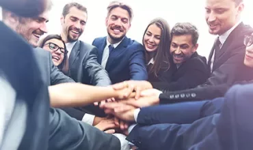 Gruppo di persone in abiti formali che uniscono le mani.