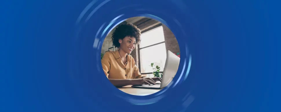 Persona sorridente al computer in una stanza illuminata