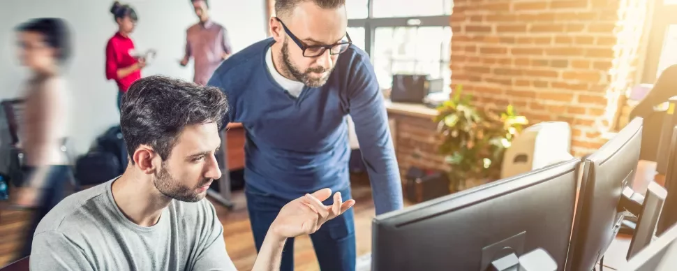Due persone lavorano al computer in un ufficio moderno.