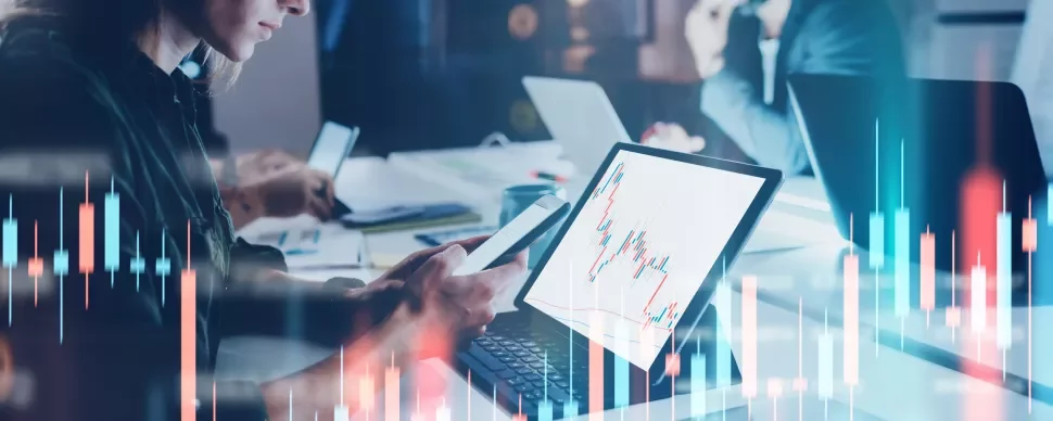 Persone lavorano al computer con grafici finanziari sullo schermo.
