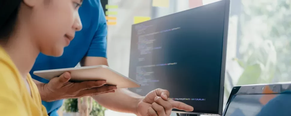 Persona che lavora al computer con codice sullo schermo.