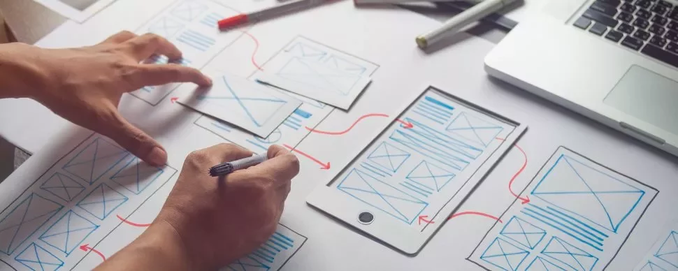Persona che disegna un wireframe su un foglio con un tablet.