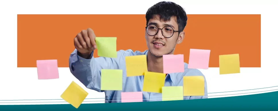Persona con occhiali sistemando post-it colorati su un vetro.