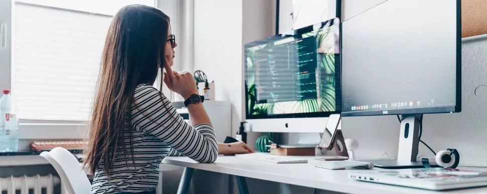 Persona al computer in ufficio moderno con schermo ampio.