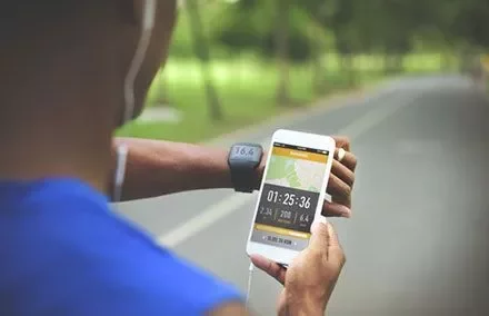 Persona che usa un'app di corsa sullo smartphone durante l'allenamento.