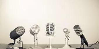 Cinque microfoni vintage sul tavolo pronti per una conferenza stampa.