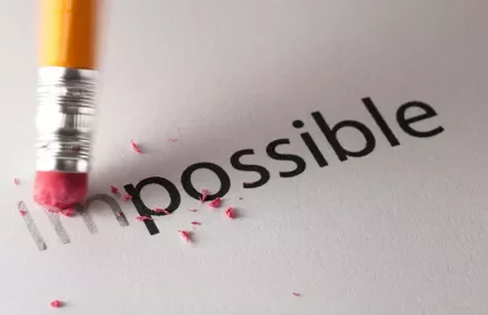 Matita che cancella la parola 'impossible' su carta.