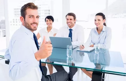 Persone in riunione sorridono intorno a un tavolo di vetro.