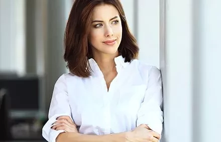 Persona in camicia bianca guarda fuori dalla finestra.