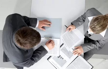 Due persone esaminano documenti in un ufficio.