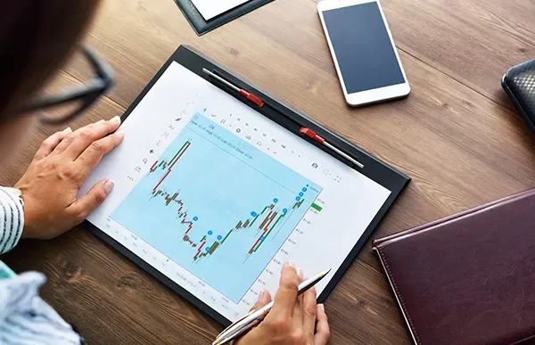 Persona che analizza un grafico finanziario su un tablet.