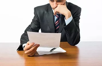 Persona in abito formale legge un documento.