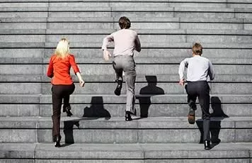 Tre persone che salgono scale in cemento all'aperto.