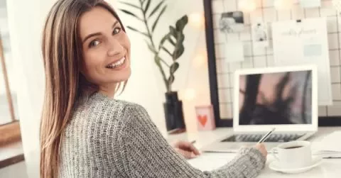Persona sorridente al lavoro a un computer portatile.