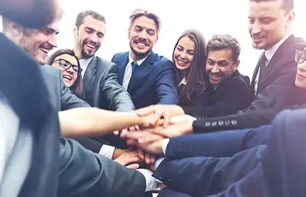 Gruppo di persone in abiti formali che si danno la mano in cerchio.