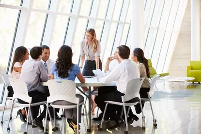Persone in riunione intorno a un tavolo in ufficio moderno.