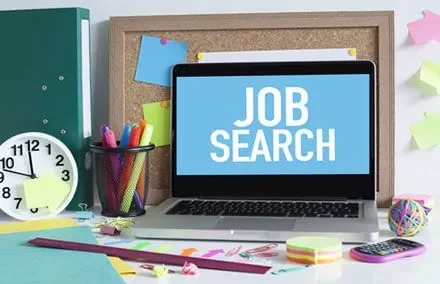 Laptop su scrivania con testo 'Job Search' sullo schermo.