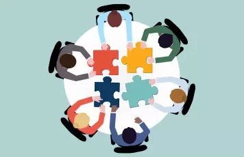 Gruppo di persone sedute attorno a un tavolo con pezzi di puzzle.