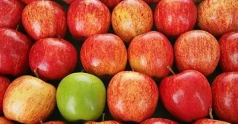 Mele rosse con una mela verde al centro.