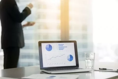 Ufficio moderno con laptop e grafici su schermo.