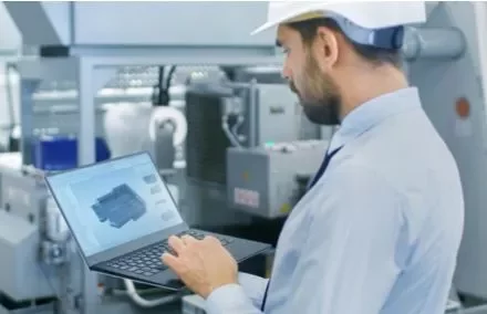 Ingegnere che lavora con un laptop in una fabbrica.