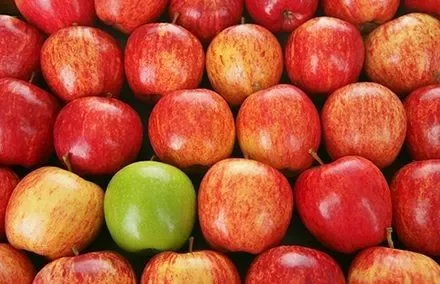 Mele rosse con una mela verde al centro.