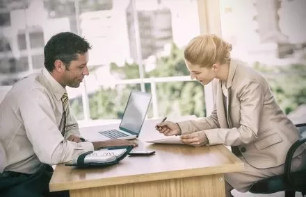 Due persone discutono in ufficio con un computer portatile.