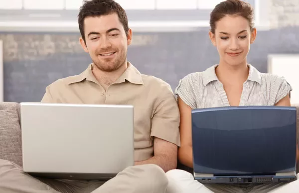 Due persone sedute con computer portatili.