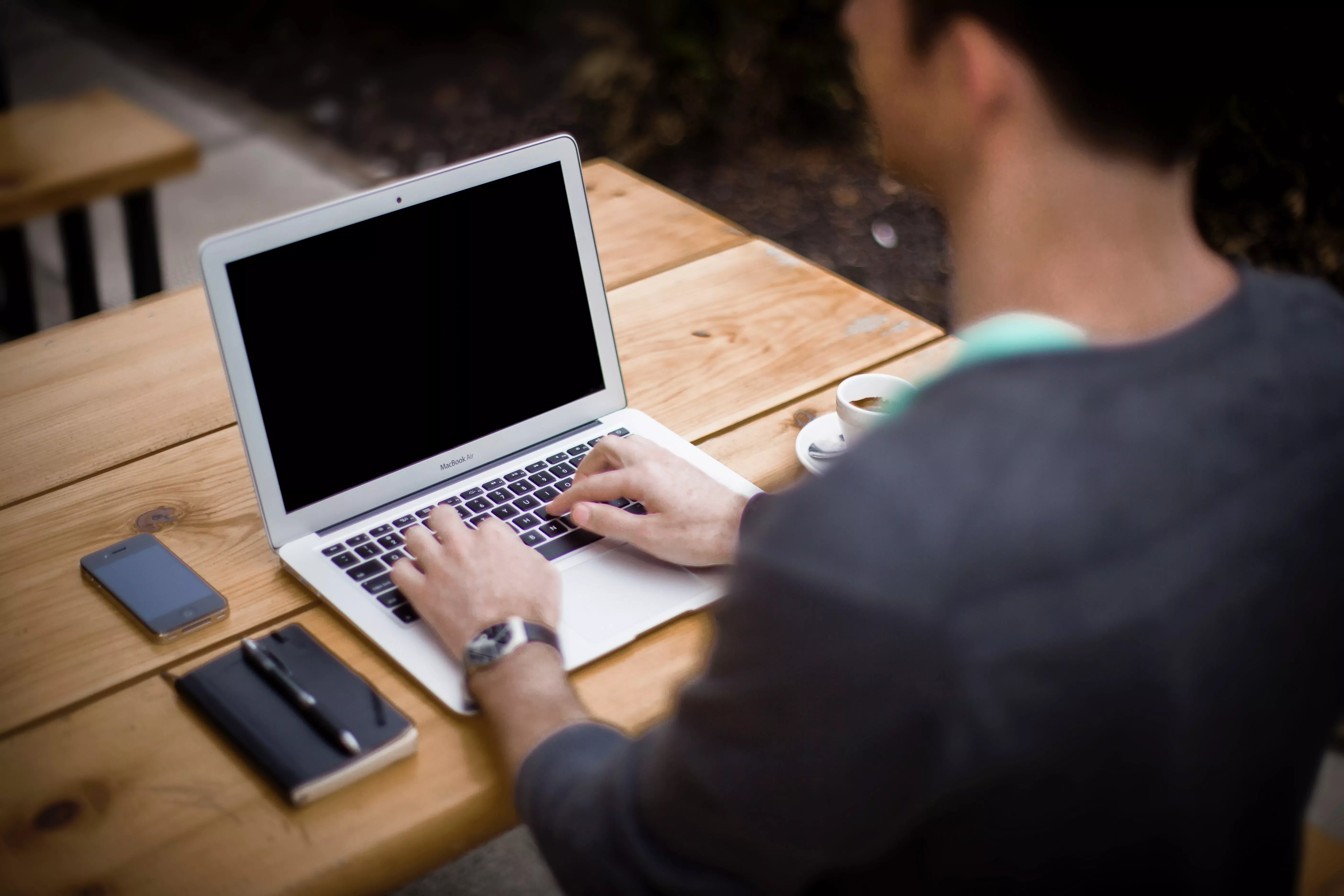Persona al computer portatile in un caffè all'aperto.