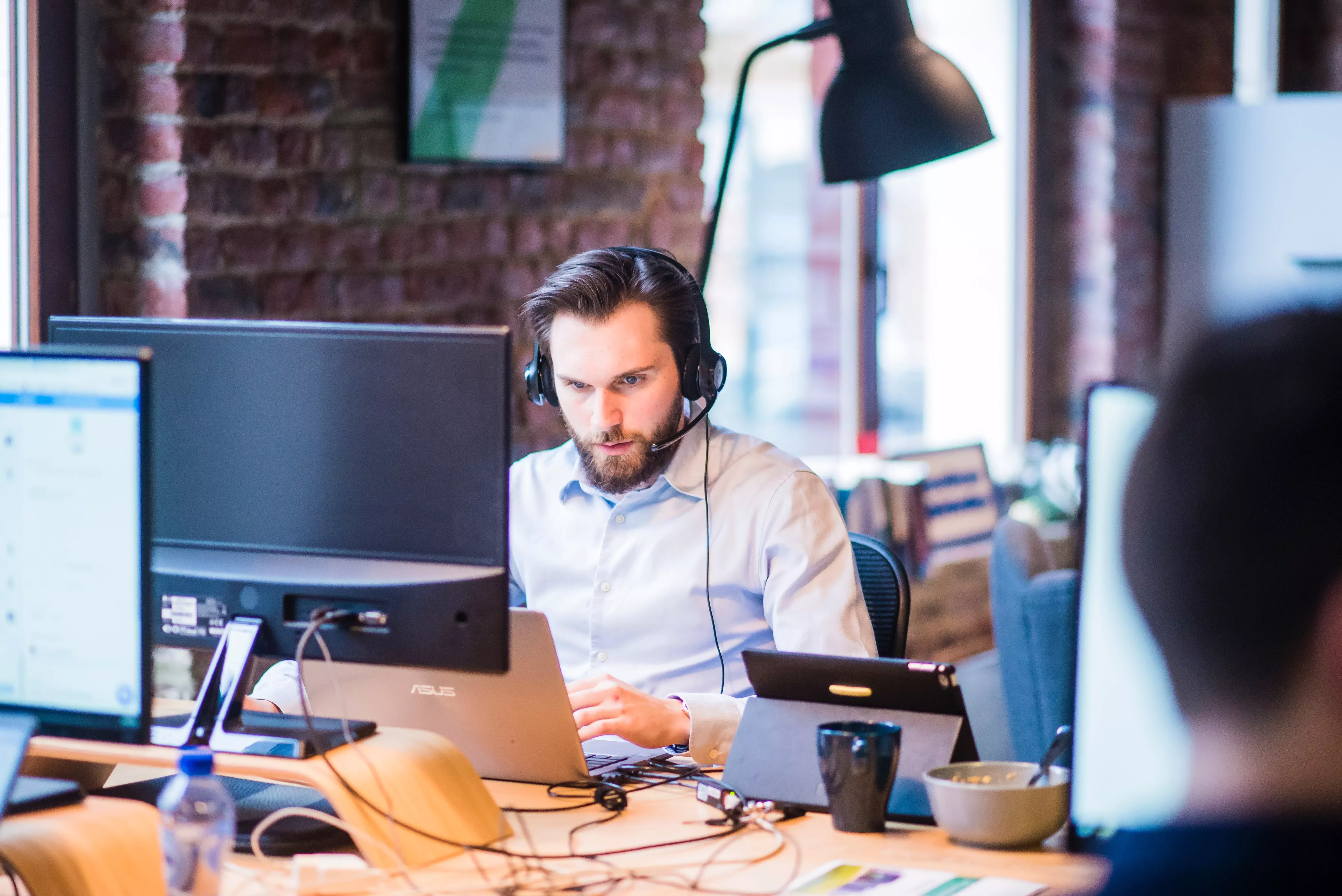 Persona al lavoro con cuffie e computer in un ufficio moderno.